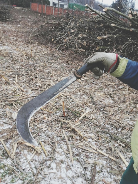 Zdjęcie Środkowa sekcja człowieka trzymającego sprzęt ogrodniczy na polu