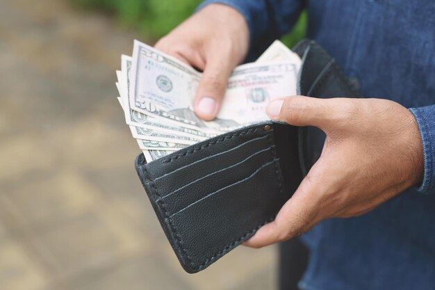 Środkowa sekcja człowieka wkładającego papierową walutę do portfela