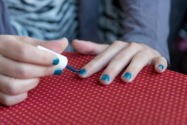 Zdjęcie Środkowa sekcja kobiety nakładającej lakier do paznokci przy stole