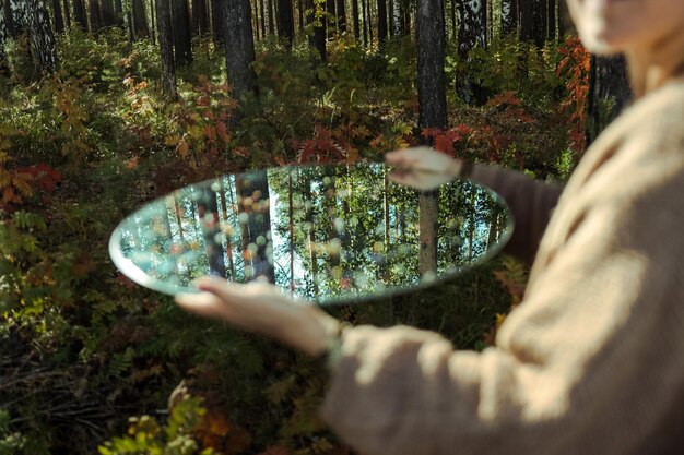Zdjęcie Środkowa sekcja kobiety trzymającej lustro w lesie