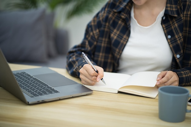 Środkowa sekcja kobiety używającej laptopa na stole
