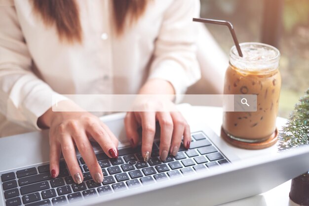 Środkowa sekcja kobiety używającej laptopa przez drinka na stole