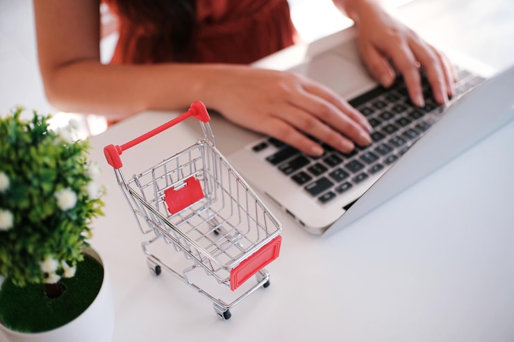 Zdjęcie środkowa sekcja kobiety używającej laptopa przy koszyku na stole