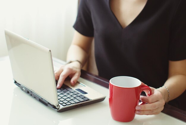 Zdjęcie Środkowa sekcja kobiety używającej laptopa przy stole