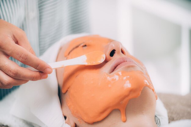 Zdjęcie Środkowa sekcja kosmetyczki nakładającej maskę na twarz kobiety