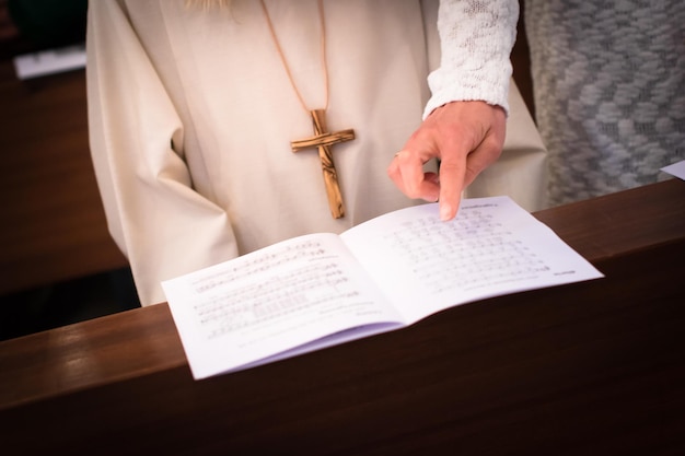 Zdjęcie Środkowa sekcja matki wskazującej na arkusz muzyczny przez córkę w kościele podczas pierwszej komunii