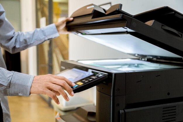 Zdjęcie Środkowa sekcja mężczyzny drukującego papierowy fotokopiator w biurze