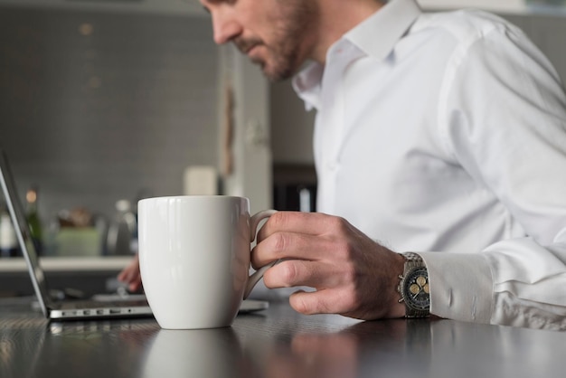Zdjęcie Środkowa sekcja mężczyzny pijącego kawę w kuchni