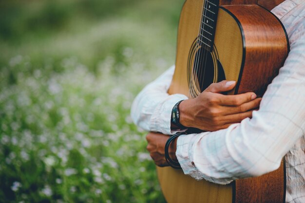 Środkowa Sekcja Mężczyzny Trzymającego Gitarę W Parku