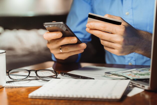 Zdjęcie Środkowa sekcja mężczyzny używającego telefonu komórkowego na stole