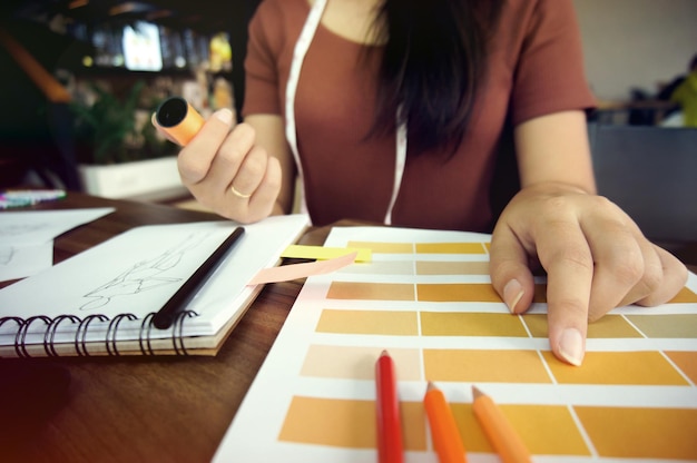Zdjęcie Środkowa sekcja projektanta mody trzymającego nici podczas używania próbki koloru przy stole