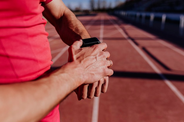 Środkowa sekcja sportowca noszącego inteligentny zegarek na torze sportowym