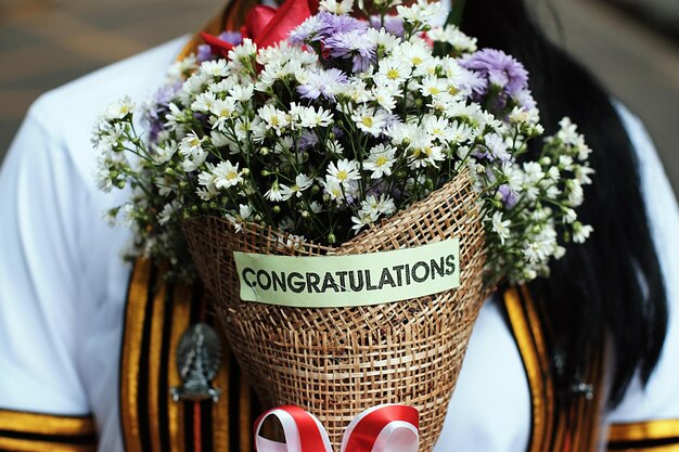 Zdjęcie Środkowy odcinek kobiety z tekstem z gratulacjami na bukietie kwiatów
