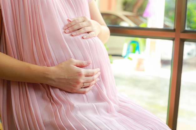 Zdjęcie Środkowy przekrój kobiety w ciąży przez okno w domu