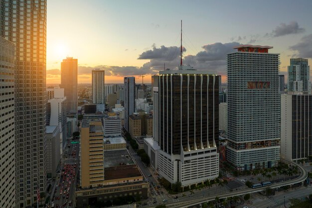 Śródmiejska dzielnica Miami Brickell na Florydzie USA o zachodzie słońca Wysokie budynki drapaczy chmur i ulica z samochodami i ruchem Metrorail we współczesnym amerykańskim centrum miasta