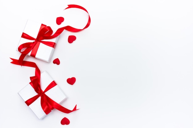 St Valentine Day card concept Białe pudełko z dużą czerwoną kokardą i lśniące ozdoby w kształcie serca na białym tle z miejsca kopiowania tekstu Zdjęcie wysokiej jakości