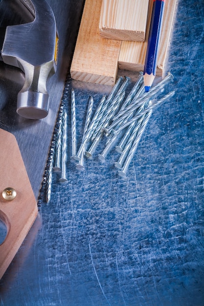 Stalowe gwoździe młotek drewniane kołki ołówek do metalu na zarysowanej koncepcji konstrukcji metalicznej powierzchni vintage