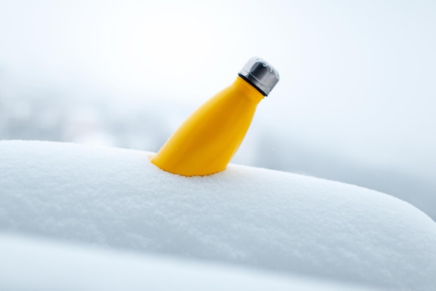 Stalowy termos o żółtym kolorze w śniegu Zbliżony widok Wielokrotny termos