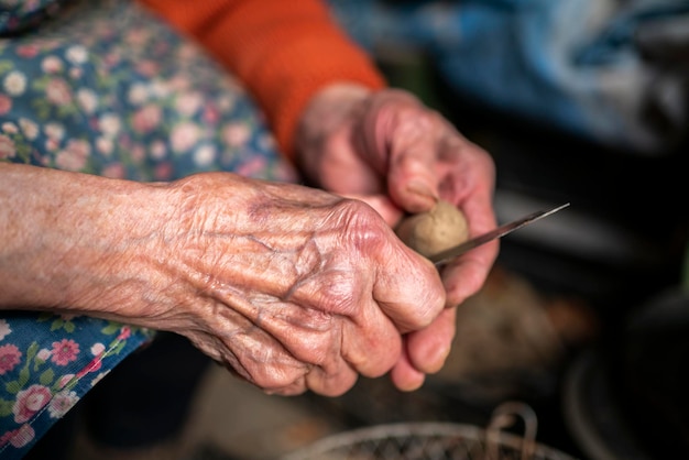 Stara babcia przygotowuje ziemniaki do gotowania przeciwstawnego bydła