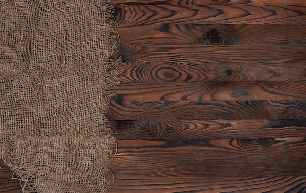 Stara burlap tkaniny pielucha na brown drewnianym tle, odgórny widok