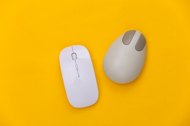 Stara i nowoczesna mysz komputerowa na żółtym tle. Widok z góry