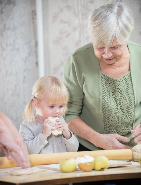 Stara kobieta robi małe placki ze swoją wnuczką dziewczyną degustującą ciasto