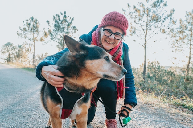 Stara kobieta z psem podczas spaceru portret w kapeluszu na wiosnę i zimę uśmiechnięta toc amera Seniorzy zdrowie psychiczne zajęcia na świeżym powietrzu Aktywny styl życia w trzecim wieku Szczęśliwa babcia