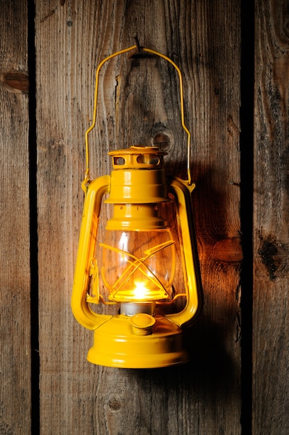 Stara latarnia naftowa wisząca na drewnianej ścianie