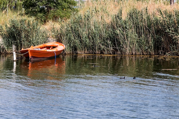 Stara łódź rybacka zacumowana przy brzegu jeziora w słoneczny letni dzień