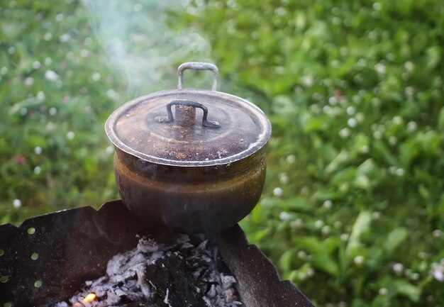 Stara patelnia na piecu na zewnątrz w trakcie przygotowywania herbaty ziołowej.