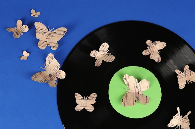 Stara płyta winylowa z papierowymi motylami na niebieskim tle