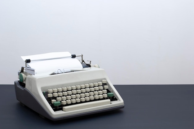 Stara retro maszyna do pisania na czarnym drewnianym stole na tle jasnej ściany