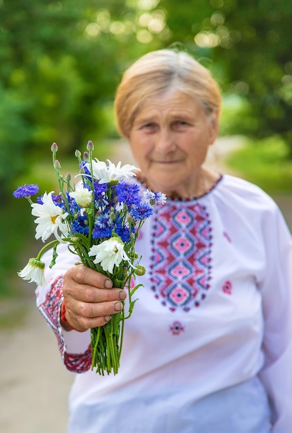 Stara ukraińska kobieta w haftowanej koszuli z bukietem kwiatów