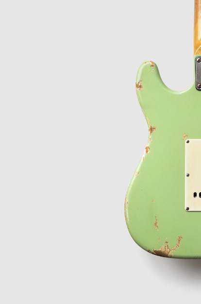 Stara zielona gitara na białym tle.