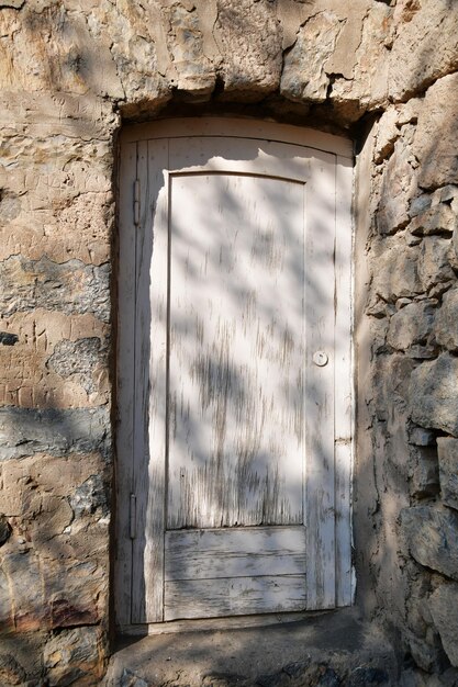 Stare Drewniane Drzwi. Drzwi Z łuszczącą Się Farbą W Kamiennej ścianie. ściana Z Dużych Kamieni.