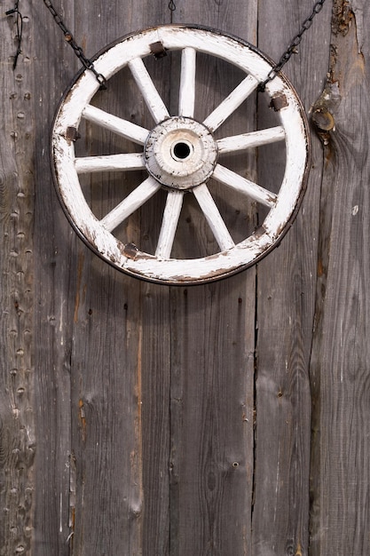 Stare drewniane koło wózka wiszące na ścianie stodoły