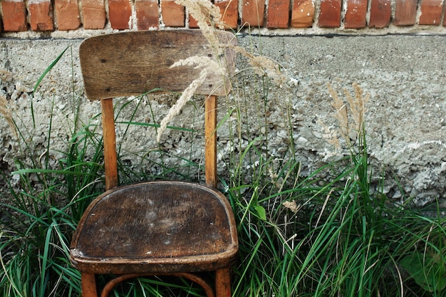 Stare drewniane krzesło i trawa na podwórku na tle starzejącego się domu w spokojnej spokojnej letniej wiosce