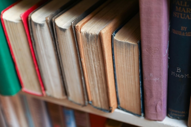 stare książki na drewnianej półce w słabo oświetlonej bibliotece atmosfera vintage, wiedza i koncepcja uczenia się
