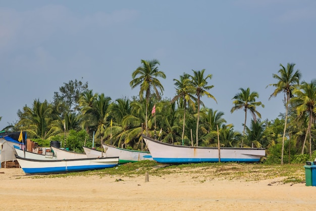 Zdjęcie stare łodzie rybackie w piasku na oceanie w indiach na niebieskim tle