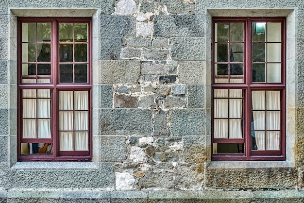 Stare okna z białymi zasłonami na kamiennej ścianie zabytkowego budynku
