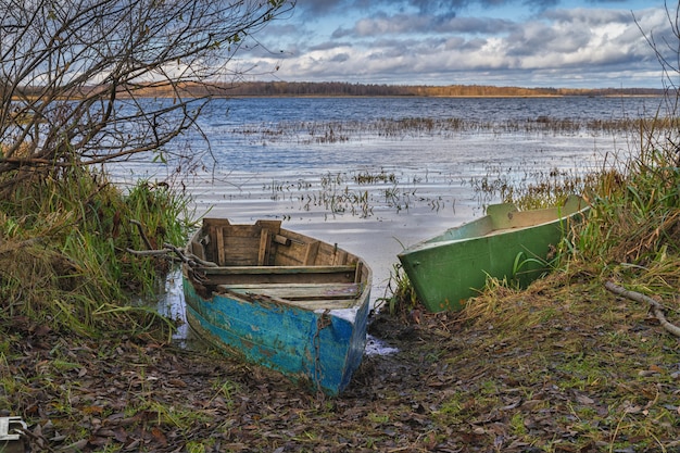 Stare połamane łodzie na brzegu małego jeziora