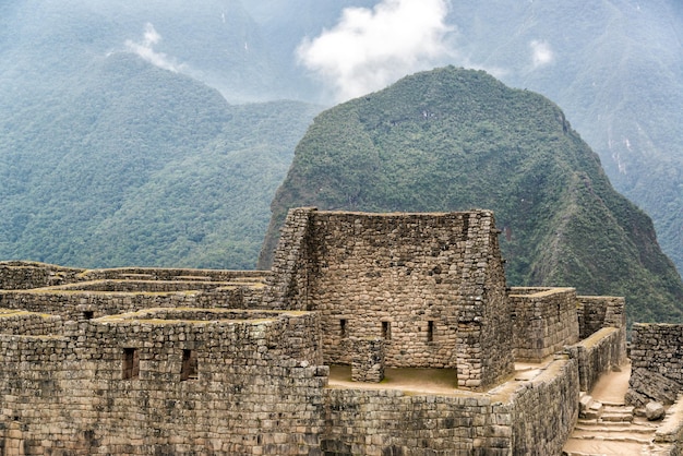 Stare ruiny na tle skalistych gór podczas mglistej pogody w machu picchu