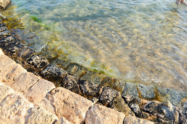 Stare starożytne żółte kamienne stopnie pokryte zielonym błotem i błotem schodzącym do oceanu jeziora morskiego