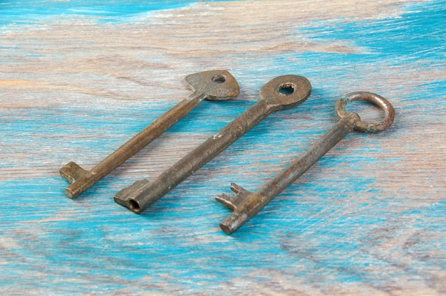 Stare żelazne klucze, szczegółowo klasyczne metalowe klucze na drewnianym tle. Skopiuj miejsce na tekst`