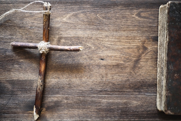 Zdjęcie starożytna księga religijna i drewniany krzyż na tle drewnianego i juty