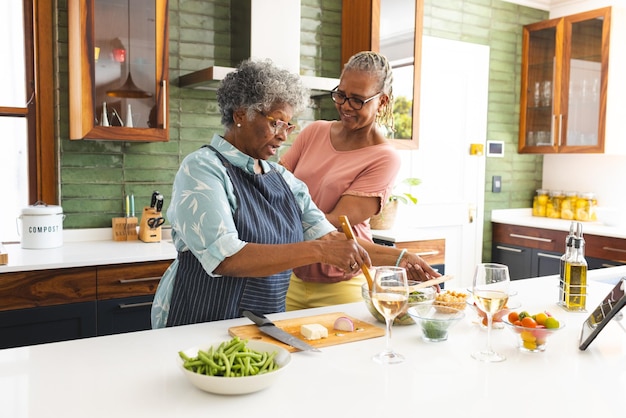 Starsza afroamerykańska kobieta i starsza mieszana kobieta gotują razem w kuchni