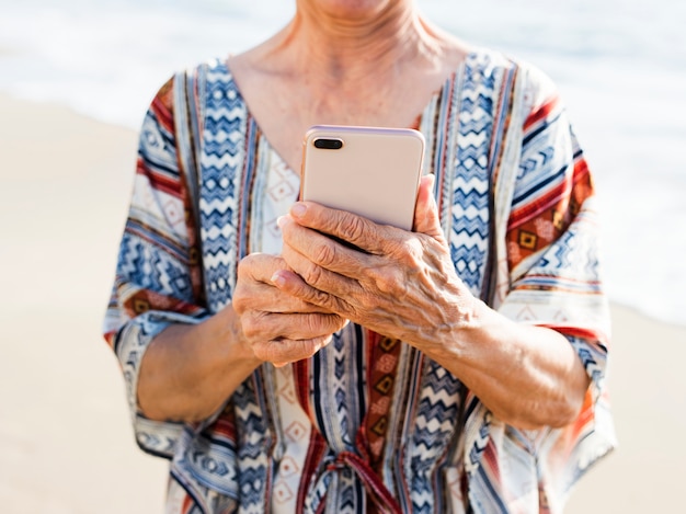 Starsza Azjatycka Kobieta Używa Telefon Przy Plażą