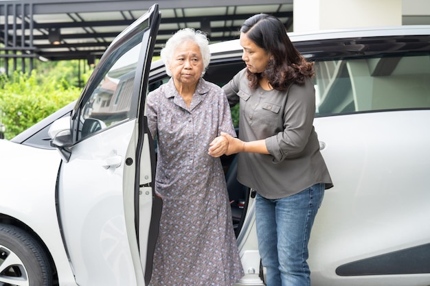Starsza azjatycka pacjentka siedząca na chodziku przygotowuje się do jej samochodu, zdrowej, silnej koncepcji medycznej