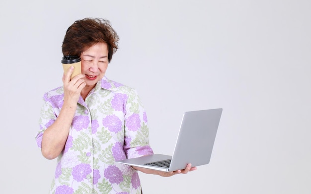 Starsza ciotka azjatycka jako starsza nauczycielka grająca na laptopie biznesowym, aby wyjaśnić promocję sprzedaży i komunikat reklamy publicznej urządzenia elektronicznego. Babcia przedstawia informacje o technologii dla emerytowanej osoby dorosłej.