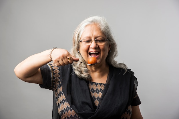 Starsza indyjska azjatycka dama je słodki Gulab Jamun z łyżką